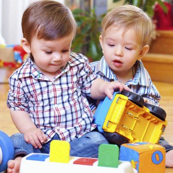Two toddlers play together at nursery