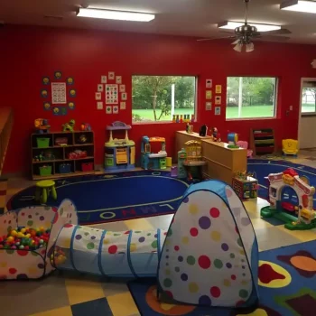 A nursery and daycare classroom with red walls and lots of games